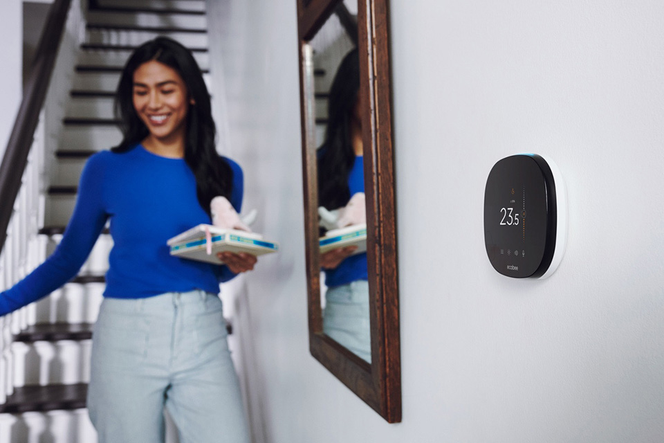 woman going down the stairs with a smart thermostat